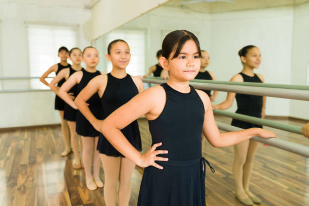 Elementary girls students taking a ballet class and learning a choreography dance next to the studio mirror